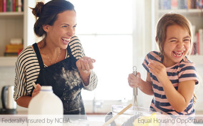 woman with flour on her apron laughing while baking with daughter